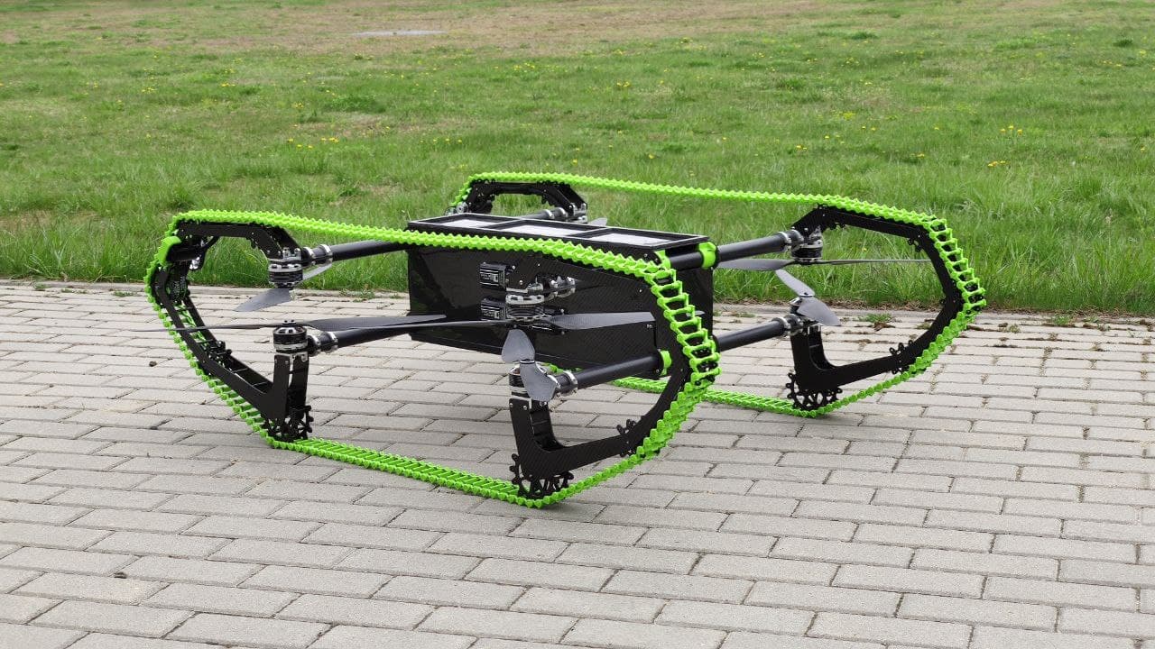 HUUVER on the ground in drive configuration — carbon-fibre chassis carried between two large green-tracked drive units.